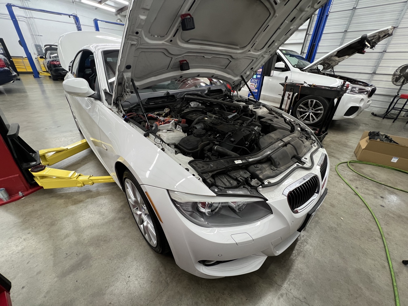 White BMW coupe raised on the shop lift