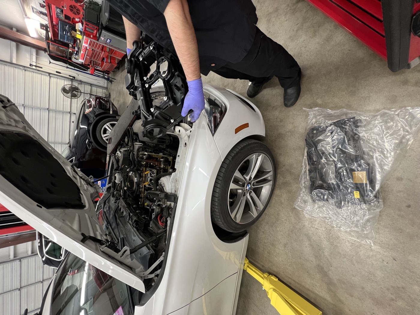 Technician in gloves working on the front end of a BMW