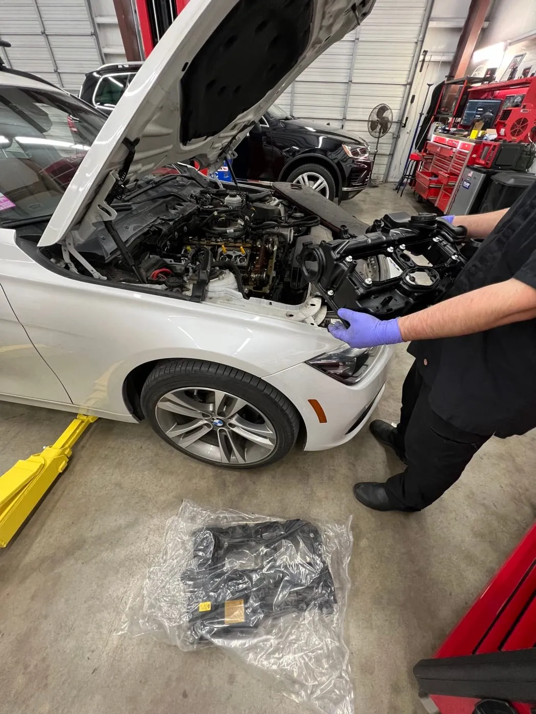 Technician in gloves working on the front end of a BMW